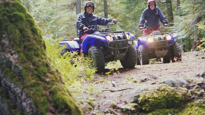 Couple riding ATV's through forest, portrait