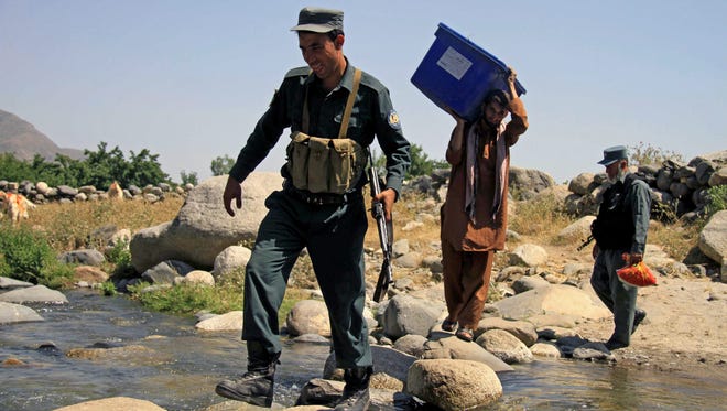 Afghan policemen escort Independent Election Commission workers as they transfer ballot boxes and electoral materials to a remote area in the Dara-I-Nur district of Nangarhar Province, Afghanistan, in June.