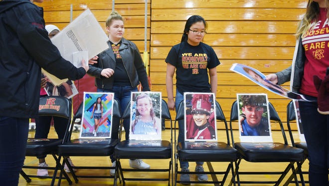 Roosevelt High School students Marlayna Goff, left center, and Jueun Nam, right center, organize photos of 17 people killed in the Parkland, Florida shooting in response to National Walkout Day Wednesday, March 14, in response to the Parkland, Florida shooting.