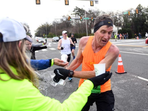 Richard Greve is handed water at the 8th mile of the