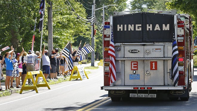 A Hingham fire truck flying the "thin blue line" flag passes police supporters on Central Street. Greg Derr/The Patriot Ledger