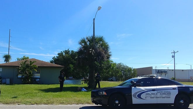 A man in handcuffs lies on the ground Friday, guarded by two Cape Coral police officers. Police said a man fled a traffic stop and crashed his car.