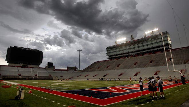 A handful of officials gather in the north end zone as the Wildcats wait out a slow moving storm cell and lightning, delaying the start of the third night of practice for more than an hour at Arizona Stadium, Friday August 7, 2015, Tucson, Ariz. Kelly Presnell / Arizona Daily Star