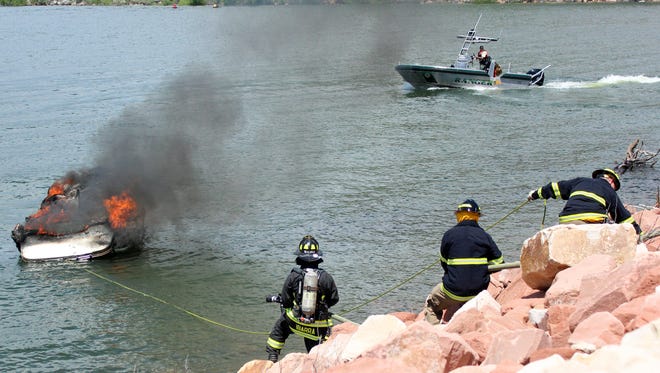 Poudre Fire Authority firefighters work to put out a blaze aboard a boat on Horsetooth Reservoir on June 12. Three people and a dog escaped the boat without injuries.