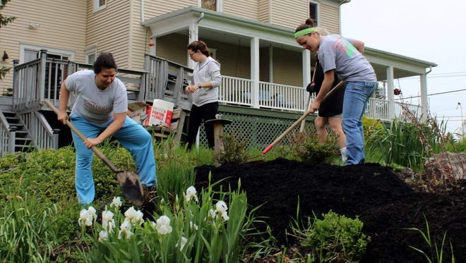 Sharon Hodge, Yazmin Fernaays and Molly Rothfuss spread mulch during Penfield’s Good Neighbor Day.
