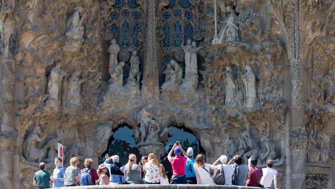 Tourists look up the Charity's Gate as they visit the Sagrada Famila Cathedral on Maundy Thursday (Holy Thursday) in Barcelona, Spain on April 13, 2017.