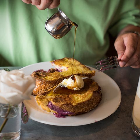 A customer drizzles maple syrup over an order of...