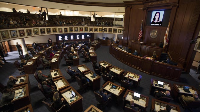 FILE - In this Feb. 21, 2018, file photo, the Florida Senate chamber is darkened while a slideshow shows each person killed in a shooting at Marjory Stoneman Douglas High School, at the state Capitol in Tallahassee, Fla. The Florida Senate spent hours debating a bill to increase school safety and restrict gun purchases in a rare Saturday session, March 3, that often turned into a debate on gun control and arming teachers in the aftermath of last month's Parkland school shootings. (AP Photo/Mark Wallheiser, File)