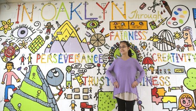 Oaklyn Public School 8th grader Krystal Abanil, 13, stands by the mural that was created by students with the help of artist Bren Bataclan, who did a weeklong artist-in-residence.