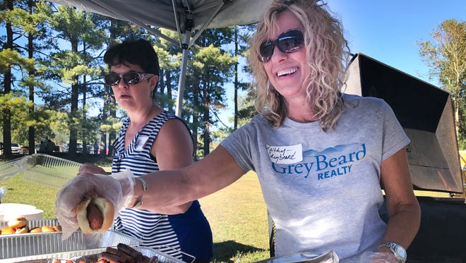 Kathy Begley, foreground, and Renda Barnes of Greybeard Realty serve hot dogs during the tailgate party at Owen Middle School.