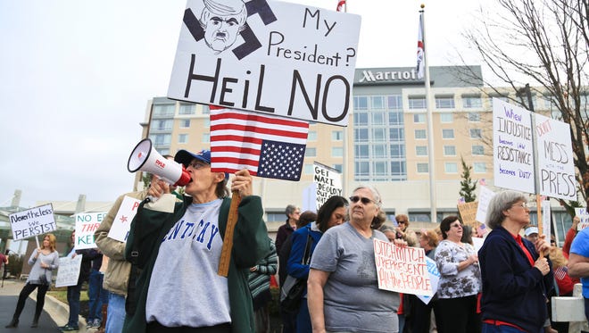 Jody Lambert of Georgetown, Ky. uses a megaphone to chant "Ditch Mitch" and other anti-McConnell sentiments outside the Louisville Marriott East with around 500 protestors Wednesday. McConnell spoke at the Jeffersontown Chamber of Commerce luncheon.