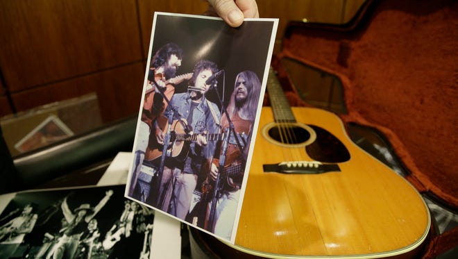 In this photo made Friday, Oct. 13, 2017, Garry Shrum, a music memorabilia specialist at Heritage Auctions, holds a photo of that displays an acoustic guitar that belonged to Bob Dylan in Dallas. Heritage Auctions said the 1963 Martin D-28 acoustic guitar will be offered up Nov. 11 in Dallas. (AP Photo/LM Otero)