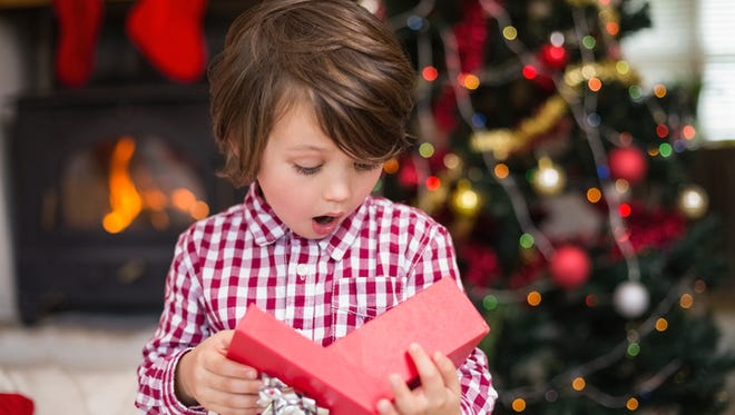 Shocked little boy looking at gift at home in the living room
