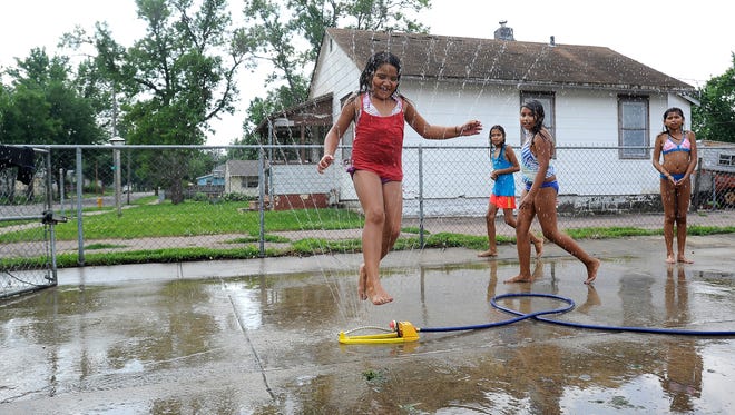 Ravea Chinn jumps through the sprinkler as Gwen White, Kyla Chinn and Kalista Howard wait their turn in the Whittier neighborhood in Sioux Falls, S.D., Thursday, July 9, 2015. 