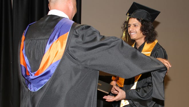 Zach Parra receives his diploma from Deming Cesar Chavez Charter High School Principal Stan Lyons during the commencement exercise held Thursday the Mimbres Valley Special Events Center.