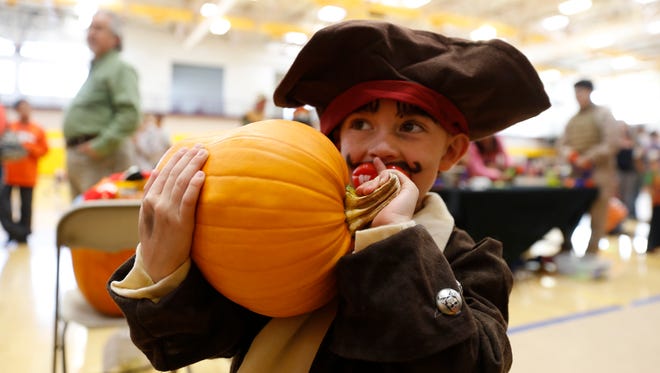 Pistol Barnes collects his pumpkin he won as a prize Saturday during the San Juan College Halloween Festival in Farmington.