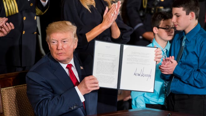 President Trump displays a presidential memorandum declaring the opioid crisis a 'public health emergency' after a speech in the White House Thursday.