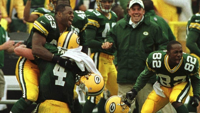 Brett Favre is embraced by George Koonce (53) after winning the game in the final seconds. At right is Desmond Howard.