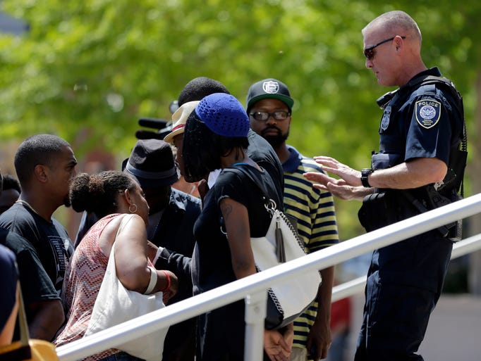 A member of the Federal Protective Service asks demonstrators to stay off the steps leading to the Thomas F. Eagleton federal courthouse during a protest in St. Louis. About 100 protesters marched from city hall to the courthouse as they continue to press for broader reforms to local and federal law enforcement following the shooting death of Michael Brown by police.