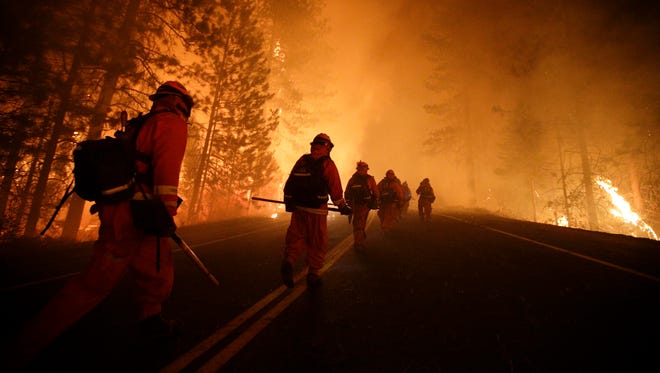 Inmate firefighters walk along state Highway 120 as firefighters continue to battle the Rim Fire near Yosemite National Park, Calif., on Sunday.
