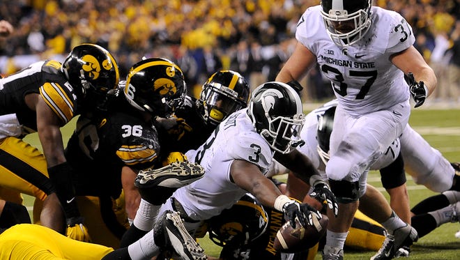 Running back LJ Scott reaches through a pile of Iowa defenders to stretch the ball across the goal line for the winning touchdown with 27 seconds left in the game December, 5, 2015, in Indianapolis in MSU's 16-13 win over Iowa in the Big Ten Championship football game.