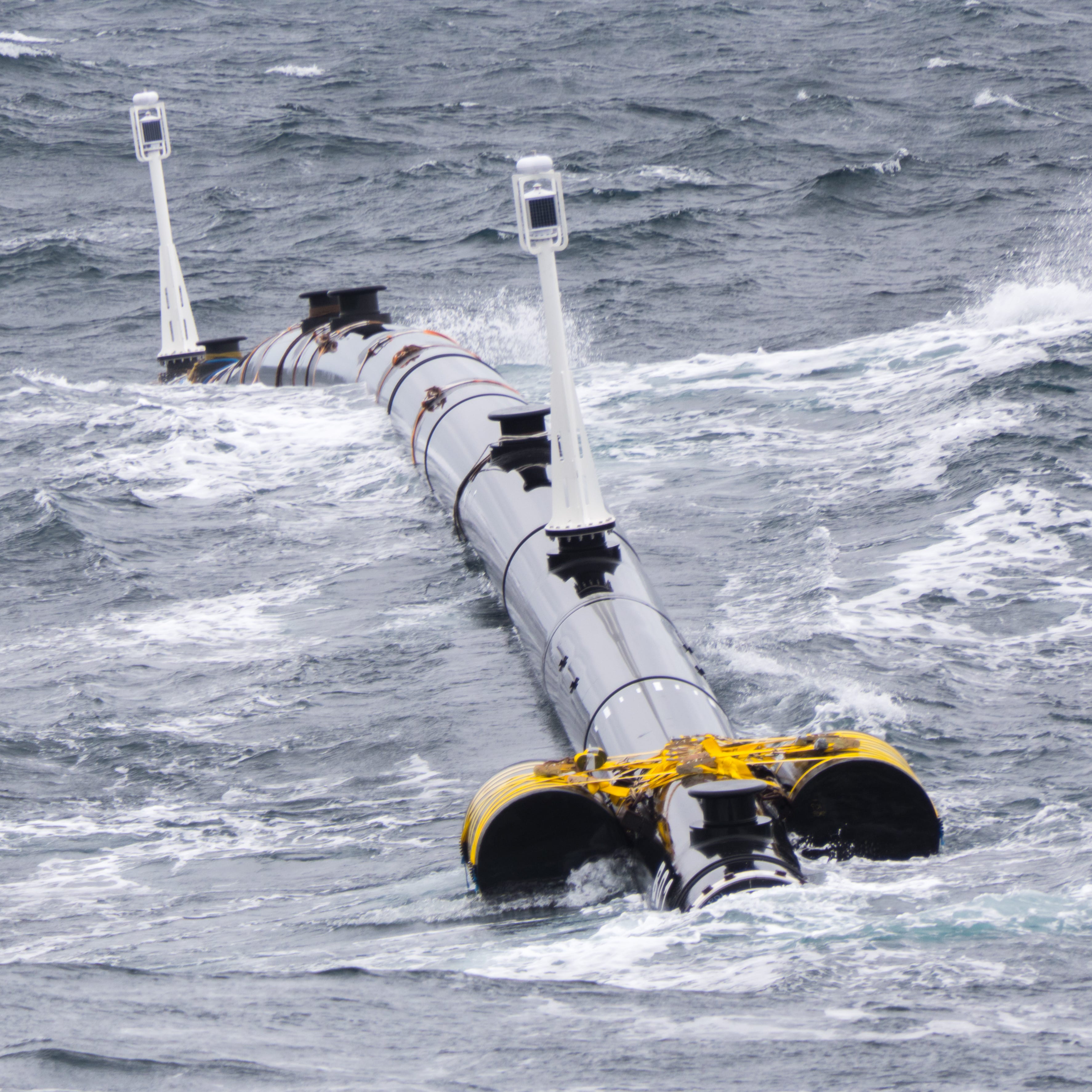 A portion of The Ocean Cleanup Project's passive system, made up of a floating series of connected pipes the length of five football fields that float at the surface of the ocean. Each closed pipe is four-feet in diameter. Below these hang a nine-foo