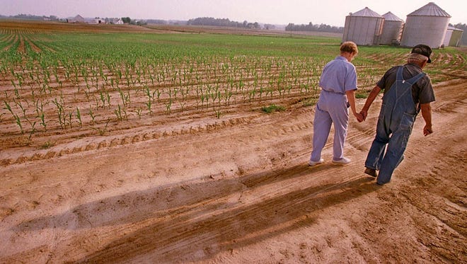 73-year-old farmer Elmer Schwiersch and his wife of fifty- years Viola, cast their shadows on dirt as they make their way from their grain and corns fields in Haubstadt, Indiana.