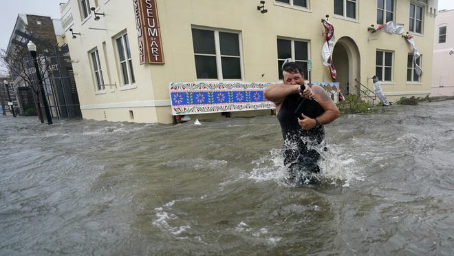 Trent Airhart wades through floodwaters, Wednesday, Sept. 16, 2020, in downtown Pensacola, Fla. Hurricane Sally made landfall Wednesday near Gulf Shores, Alabama, as a Category 2 storm, pushing a surge of ocean water onto the coast and dumping torrential rain that forecasters said would cause dangerous flooding from the Florida Panhandle to Mississippi and well inland in the days ahead.