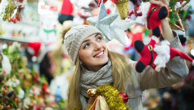 Happy glad cheerful girl choosing Christmas decoration at market in night time