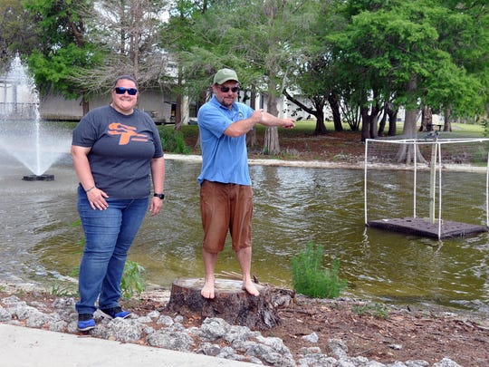 South Florida State College project manager Kendall Carson, left, and Oviedo entrepreneur Steve Edmonds place a cannabis biomat onto Lake Glenada.