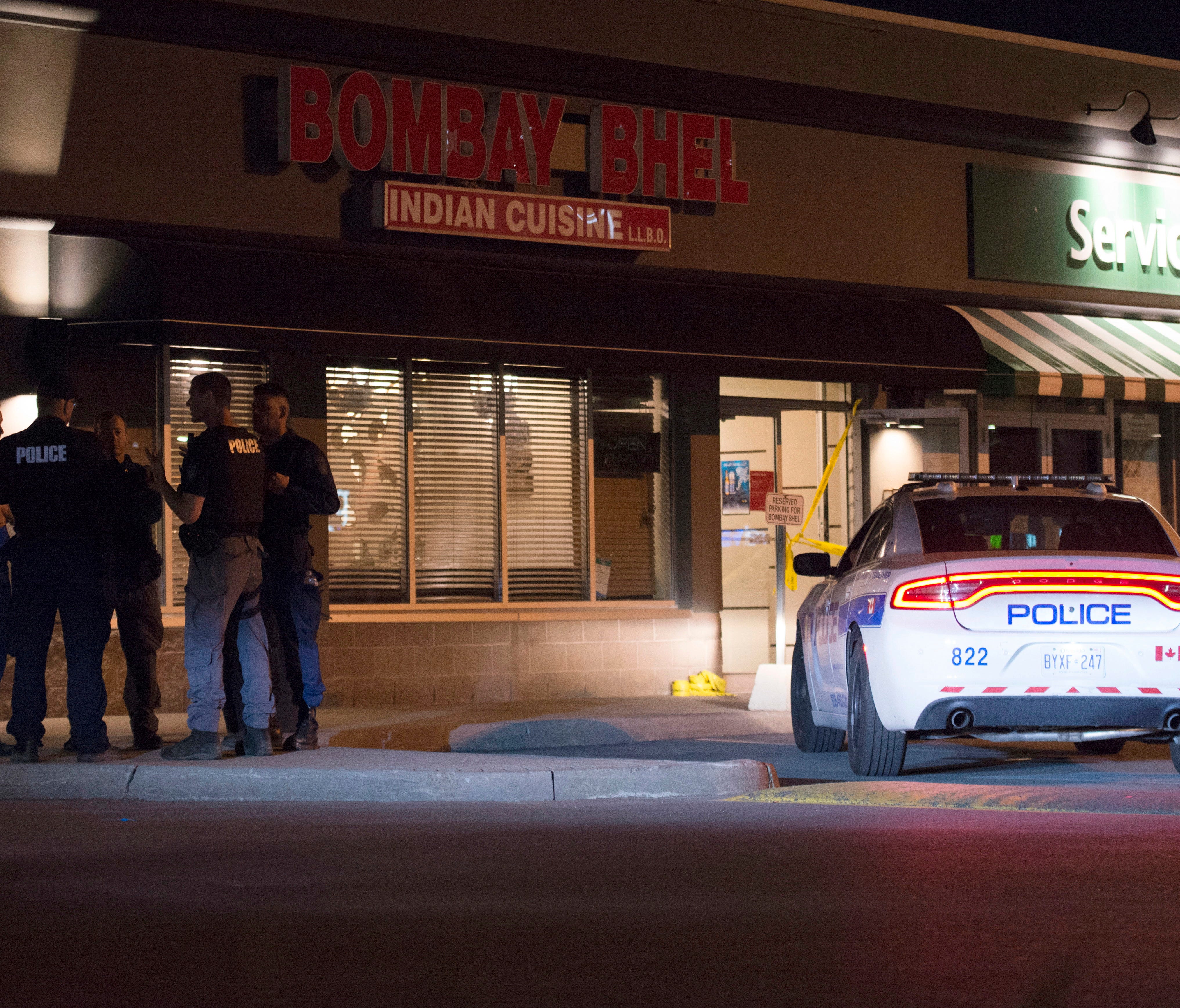Police stand outside the Bombay Bhel restaurant in Mississauga, Canada. om Friday
