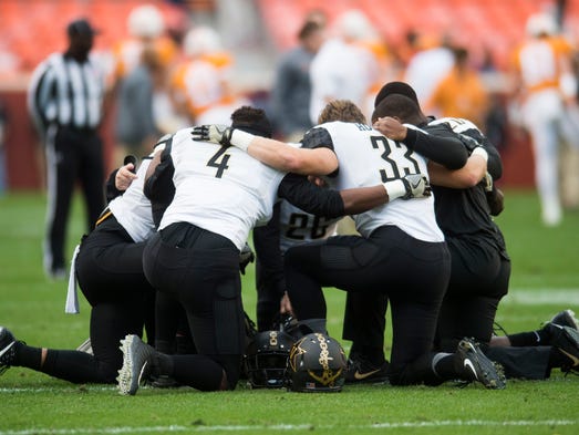 Vanderbilt players kneel before a game between Tennessee