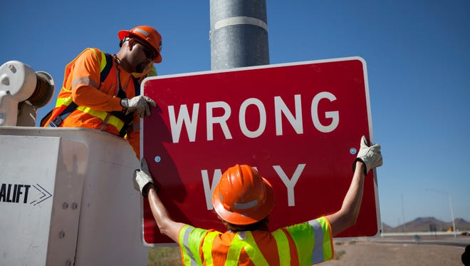 ADOT worker Daniel Gutierrez and supervisor Sean McHugh hang a larger, more prominent "wrong way" sign at the southeast corner of the Interstate 17 interchange at Carefree Highway in north Phoenix.