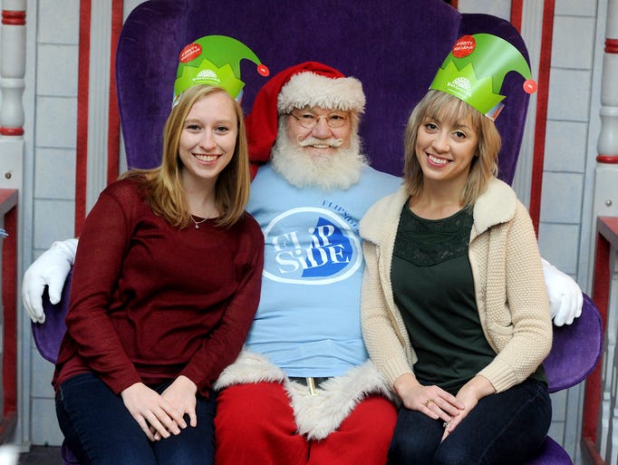 Abbey Zelko, left, and Ashley May pose with Santa at