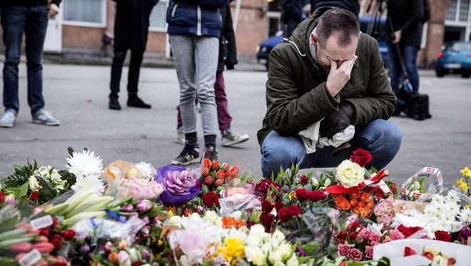A man reacts next to flowers for the shooting victims outside the "Kruttoende" cultural centre in Copenhagen, Denmark on February 15, 2015.  Two fatal attacks in the Danish capital, at a cultural center during a debate on Islam and free speech and a second outside the city's main synagogue.