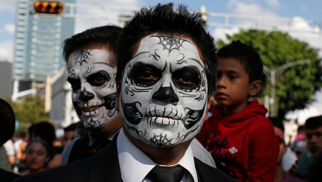 Men with their faces painted as sculls pose for a photo during a Day of the Dead parade along Mexico City's main Reforma Avenue, Saturday, Oct. 29, 2016. Hollywood movies, zombie shows, Halloween and even politics are fast changing Mexico's Day of the Dead celebrations, which traditionally consisted of quiet family gatherings at the graves of their departed loved ones bringing them music, drink and conversation.