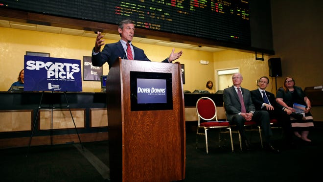 Delaware Gov. John Carney speaks in front of a tote board, Tuesday, June 5, 2018, as he introduces sports gaming inside the Race and Sports Book at Dover Downs Hotel and Casino in Dover, Del. The market for legal sports gambling in the United States widened significantly on Tuesday with the expansion of single-game sports bets in Delaware, less than a month after the U.S. Supreme Court cleared the way for states to accept the bets. (AP Photo/Patrick Semansky)
