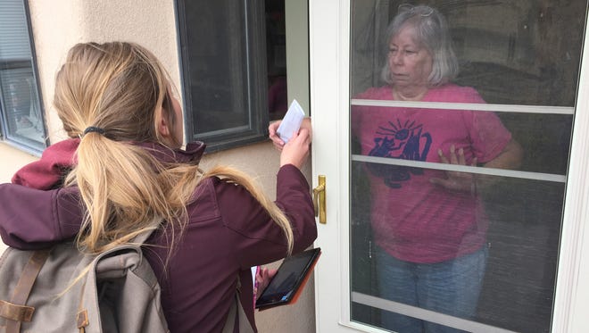 In this March 31, 2017 photo, retired Santa Fe resident Sheila Hartney, 68, receives a pamphlet promoting a plan to tax sugary sodas and other sweetened beverages from a professional canvasser in Santa Fe, N.M. Voters in New Mexico's capital city have until May 2 to decide whether to levy a new 2-cents-per-ounce tax on sugary soda and other sweetened beverages. The citywide tax would pay to expand early childhood educational programs.