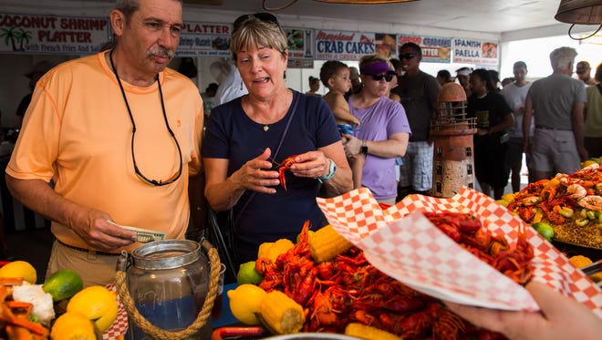 Jill Remick, right, explains to Jim Orlenko, left, the unglamorous way to properly eat a crawfish during the annual Everglades Seafood Festival in Everglades City on Saturday, Feb. 10, 2018. Remick is from Michigan but has been attending this seafood fest for 25 years.