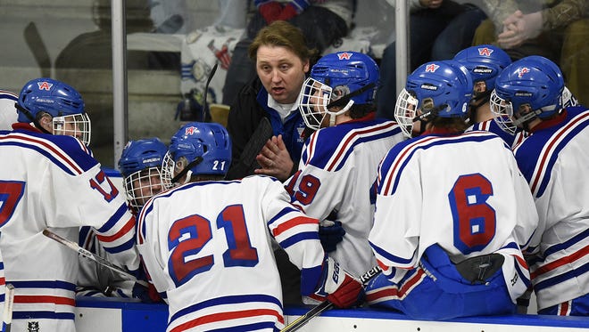 Pete Matanich talks with Apollo High School players during a hockey game.