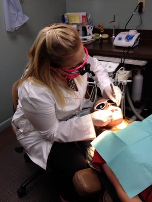 Dentist Allison Powers examines Chloe Spencer’s teeth at Milford Dental Excellence.
