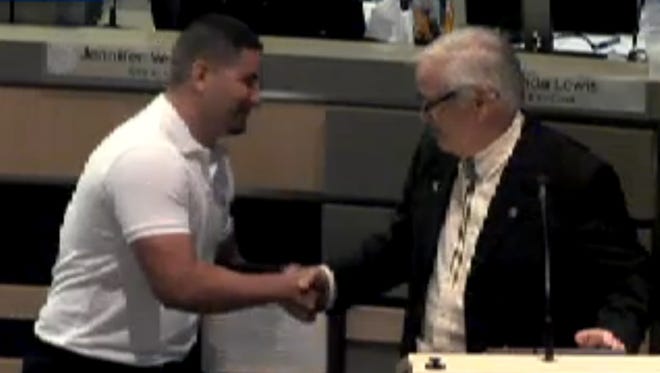 Johnny Villa, who saved an 8-year-old girl from drowning last month in Las Cruces, shakes hands with City Councilor Gill Sorg during a City Council meeting Monday. Villa received an award for his heroic actions.
