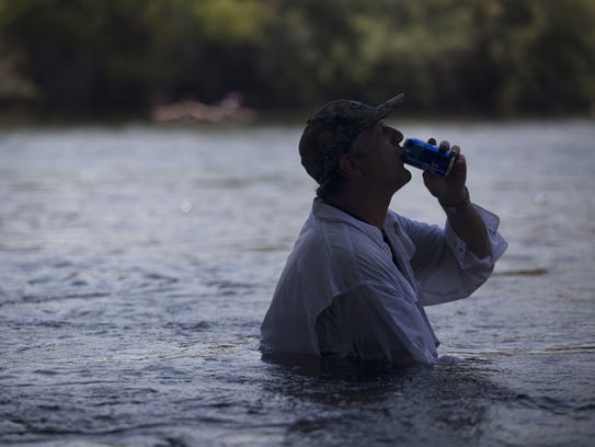 A man keeps cool sitting in the Salt River on Saturday,