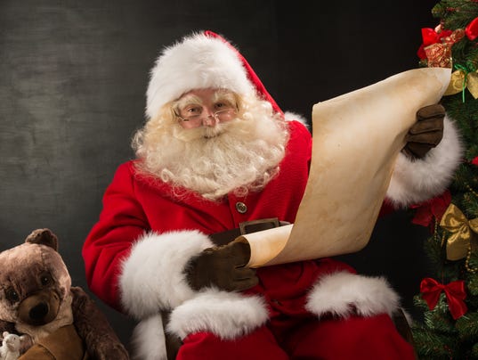Portrait of happy Santa Claus reading Christmas letter