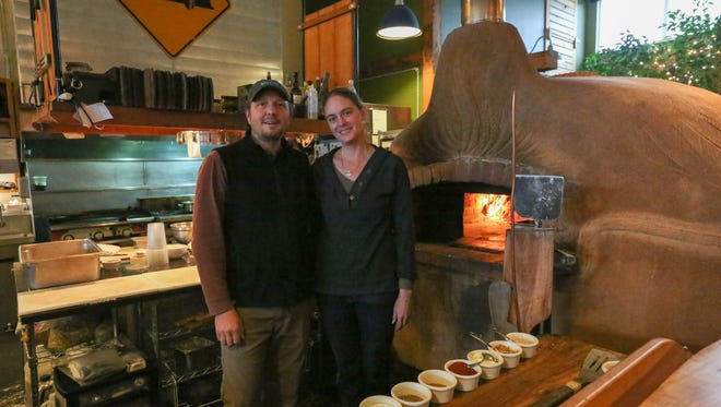 The Blue Goat owners Dave and Cassie VanDomelen stand in front of their hand-sculpted earthen oven.