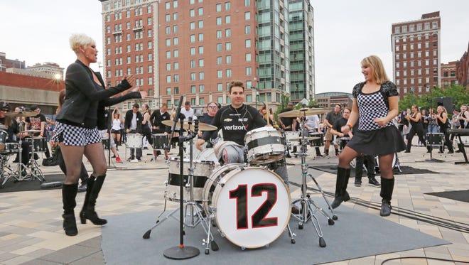 Dancers flank IndyCar driver Will Power as he plays drums during Friday's "Rock-IN-Roar 500" event on Pan Am Plaza.