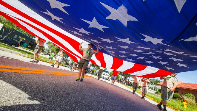 Evan Robbins of Cape Coral and with Troop 4, walked under the giant flag to hold up the middle as his troop walked in the parade. A Sept. 11 attacks memorial parade was held in Cape Coral with around 80 participants from EMS, fire, police and military units, marching bands, color guards, special floats, Veterans, etc. The community came out to show their support for the parade participants.