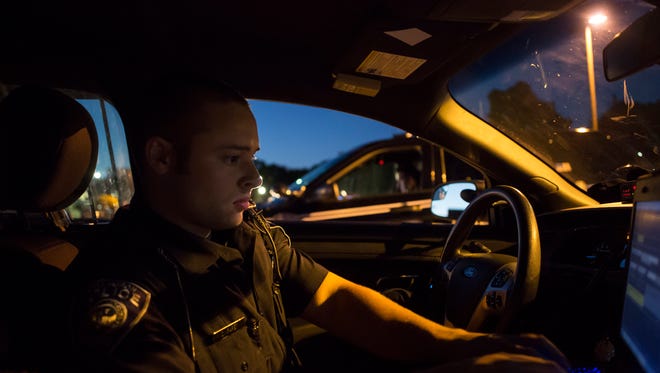 Port Huron Police Officer Derek Paret checks active calls on the computer in his patrol car while parked off of Erie Street Sept. 14, 2016, in Port Huron. If retiree debt is left unaddressed, Port Huron city residents could see a cut in services to balance the funds needed to continue paying those legacy costs.