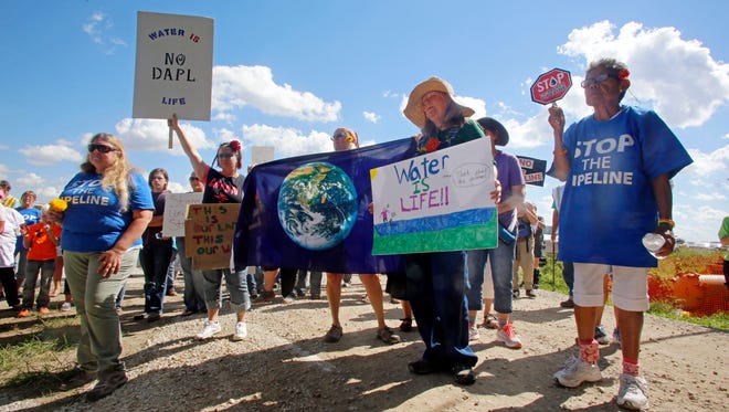 A group of people hold signs as they prepare to trespass into a Dakota Access Pipeline construction site during a protest which took place at a pipeline construction site Saturday, Sept. 17, 2016, in Montrose, Iowa.