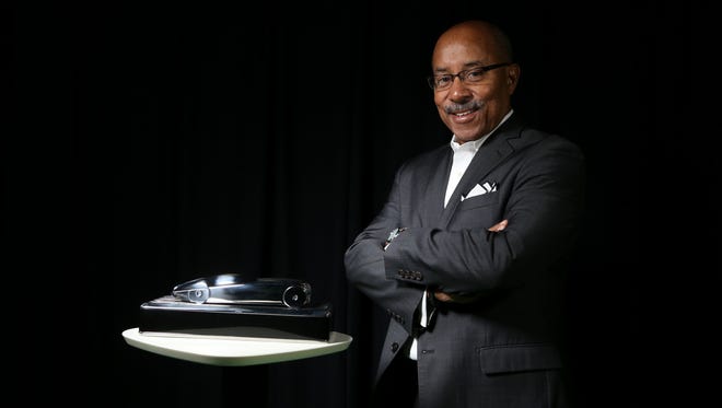 Ed Welburn, the recently retired design director at General Motors, stands with the concept car trophy that he designed for the North American Car, Truck and Utility of the Year Awards.